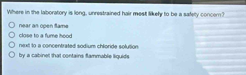 where in the laboratory is long, unrestrained hair most likely to be a safety concern?\nnear an open flame\nclose to a fume hood\nnext to a concentrated sodium chloride solution\nby a cabinet that contains flammable liquids