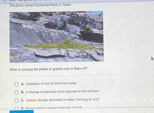 the photo shows enchanted rock in texas. what is causing the plates of granite rock to flake off? a. oxidation of iron to form iron oxide b. a change in pressure once exposed at the surface c. carbon dioxide dissolved in water, forming an acid d. strong winds carrying particles of rock