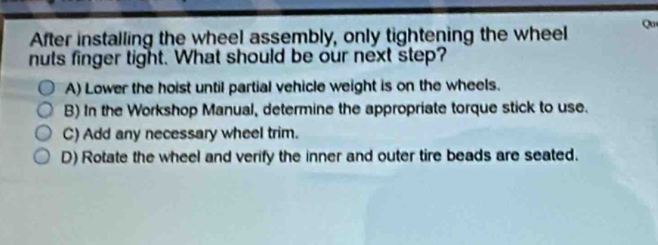 after installing the wheel assembly, only tightening the wheel nuts finger tight. what should be our next step?\na) lower the hoist until partial vehicle weight is on the wheels.\nb) in the workshop manual, determine the appropriate torque stick to use.\nc) add any necessary wheel trim.\nd) rotate the wheel and verify the inner and outer tire beads are seated.