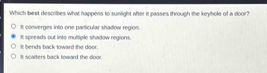 which best describes what happens to sunlight after it passes through the keyhole of a door?\nit converges into one particular shadow region.\nit spreads out into multiple shadow regions.\nit bends back toward the door.\nit scatters back toward the door.