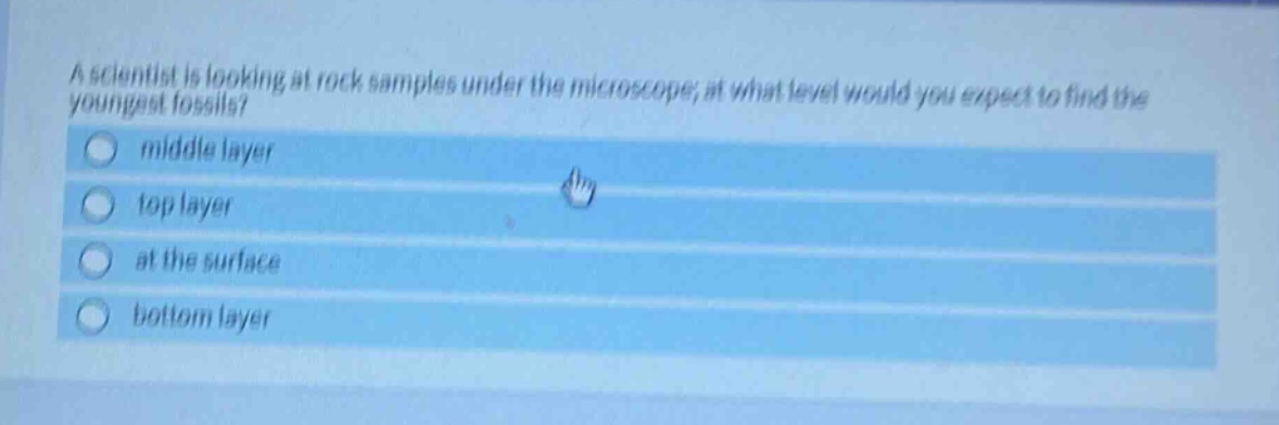 a scientist is looking at rock samples under the microscope; at what level would you expect to find the youngest fossils?\nmiddle layer\ntop layer\nat the surface\nbottom layer