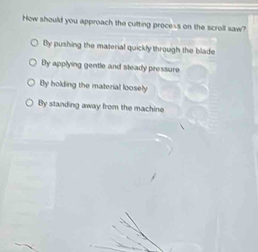 how should you approach the cutting process on the scroll saw?\nby pushing the material quickly through the blade\nby applying gentle and steady pressure\nby holding the material loosely\nby standing away from the machine